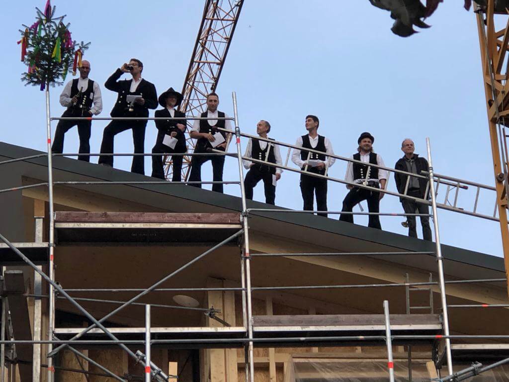 Personengruppe bei einem Richtfest auf einer Holzkonstruktion